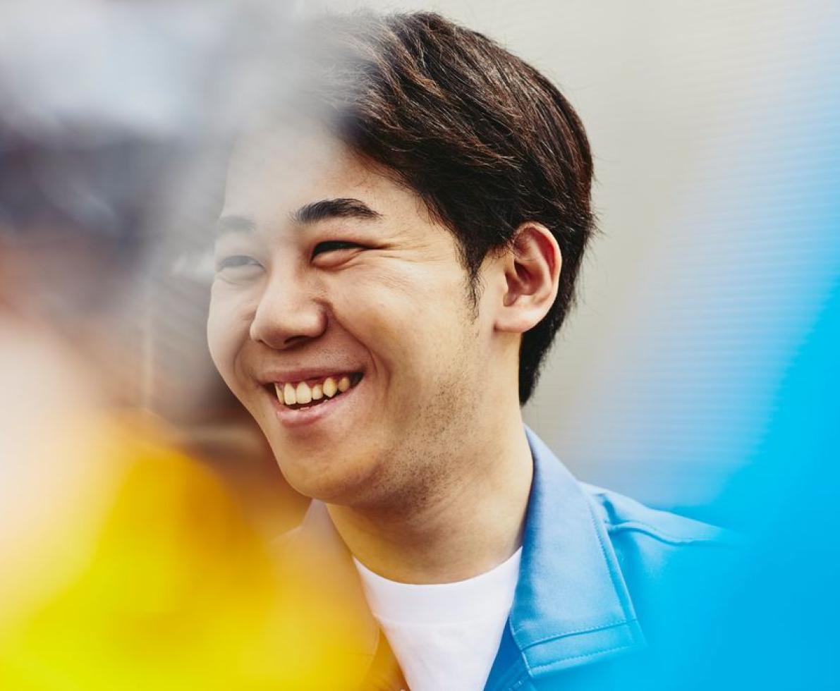 A photo of a man wearing a white shirt underneath his polo, smiling.