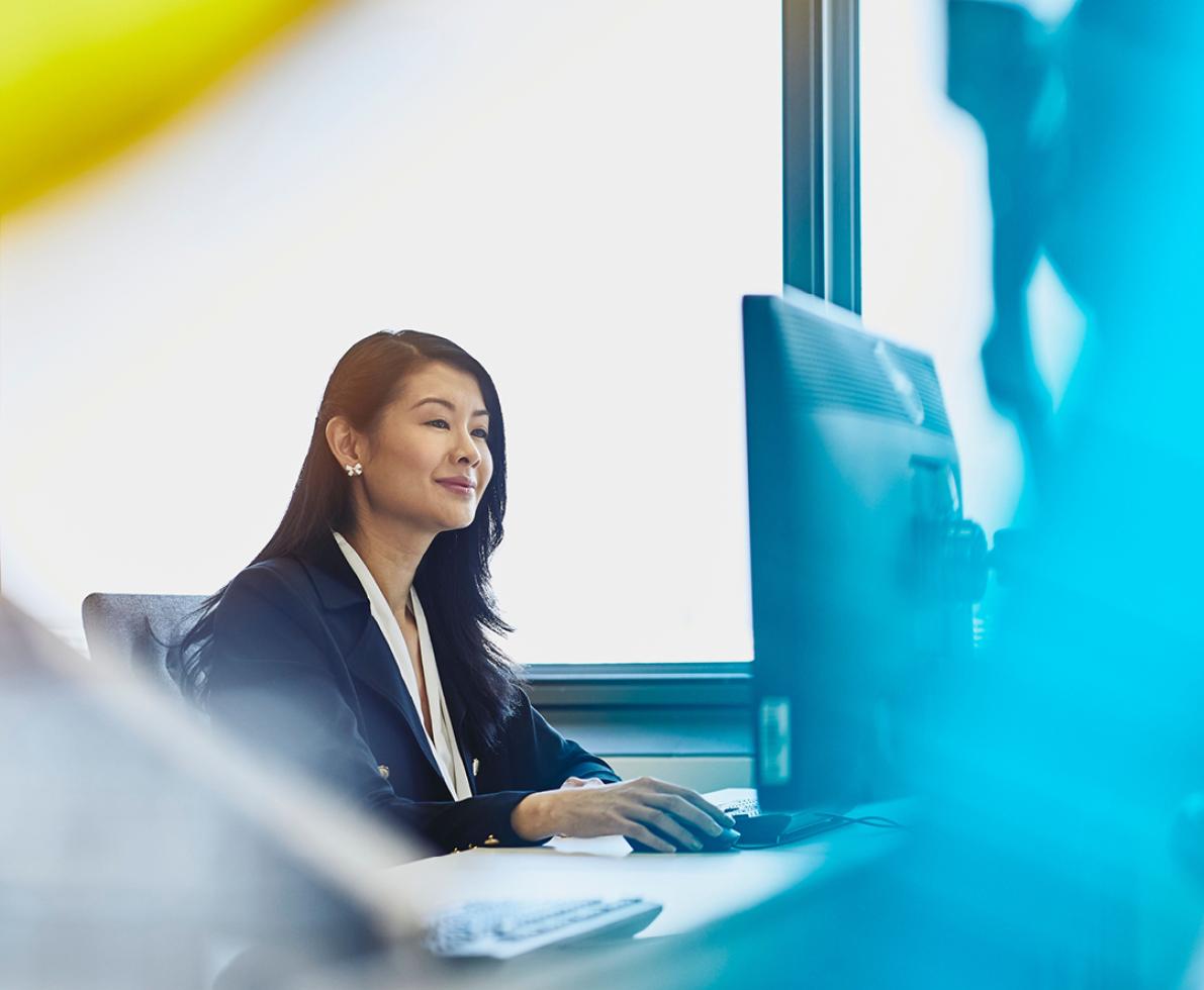 A photo of a woman in front of a PC working in the tech sector