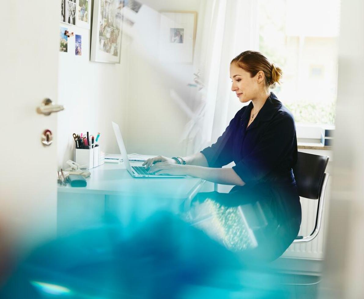 Woman working on a laptop at a desk at her home. Woman working on a laptop at a desk at her home.