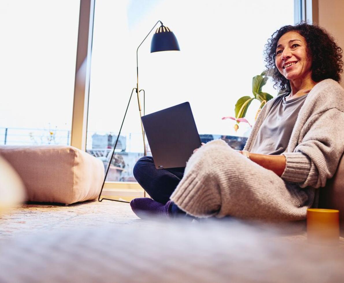 A photo of a woman sitting on the floor attending virtual recruitment events