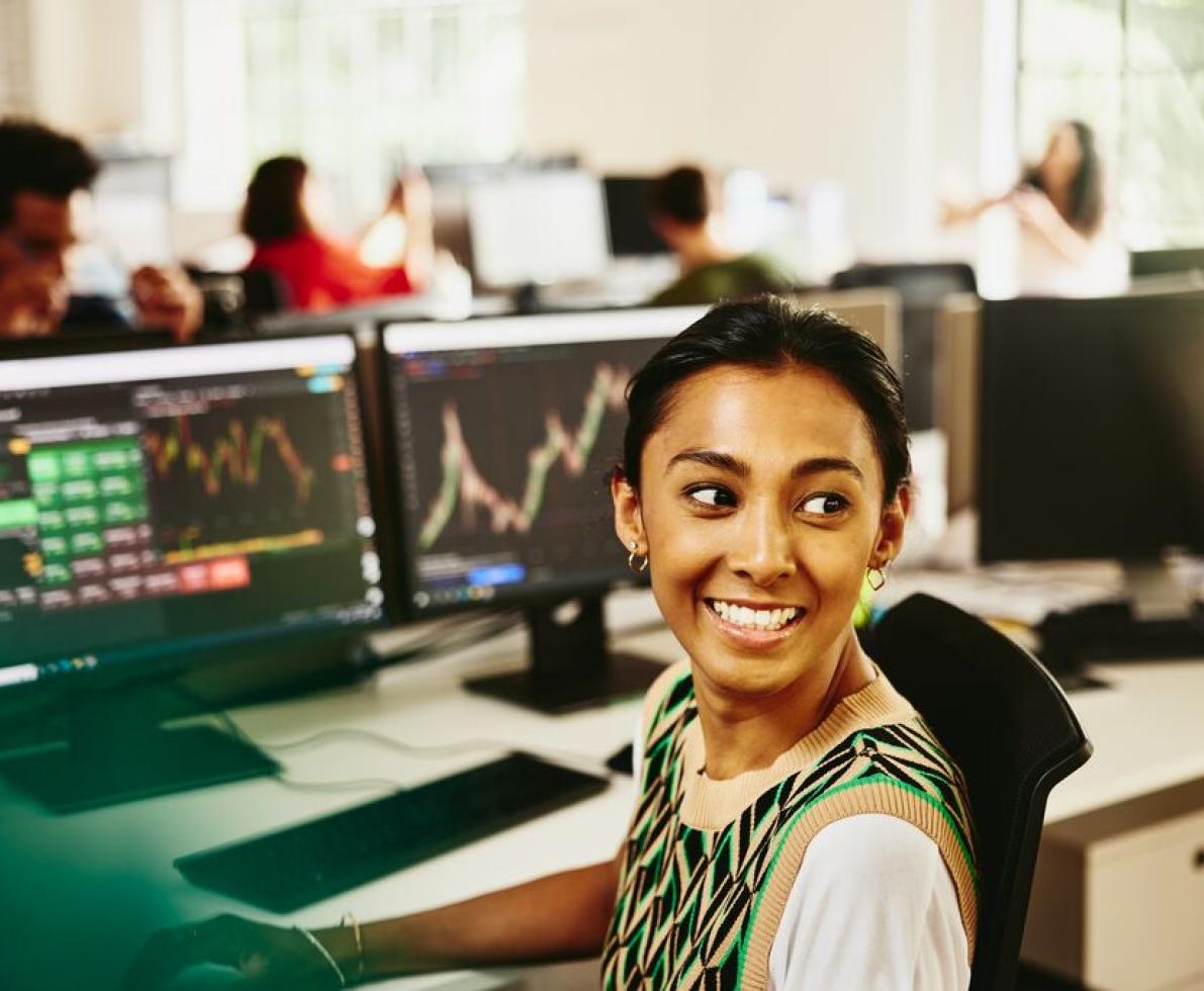 a woman smiling sitting at her desk whilst doing her work