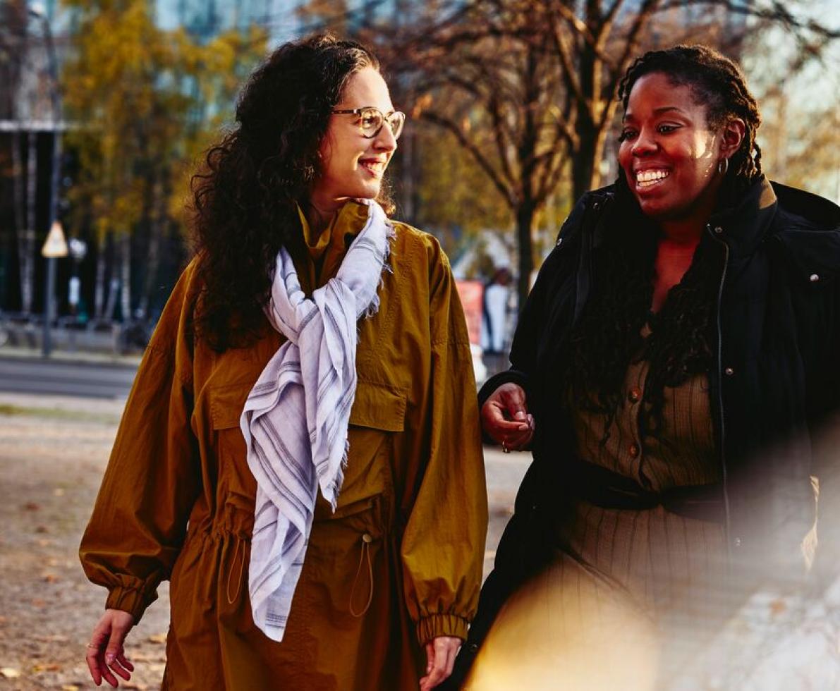 Two women wearing coats walking and chatting