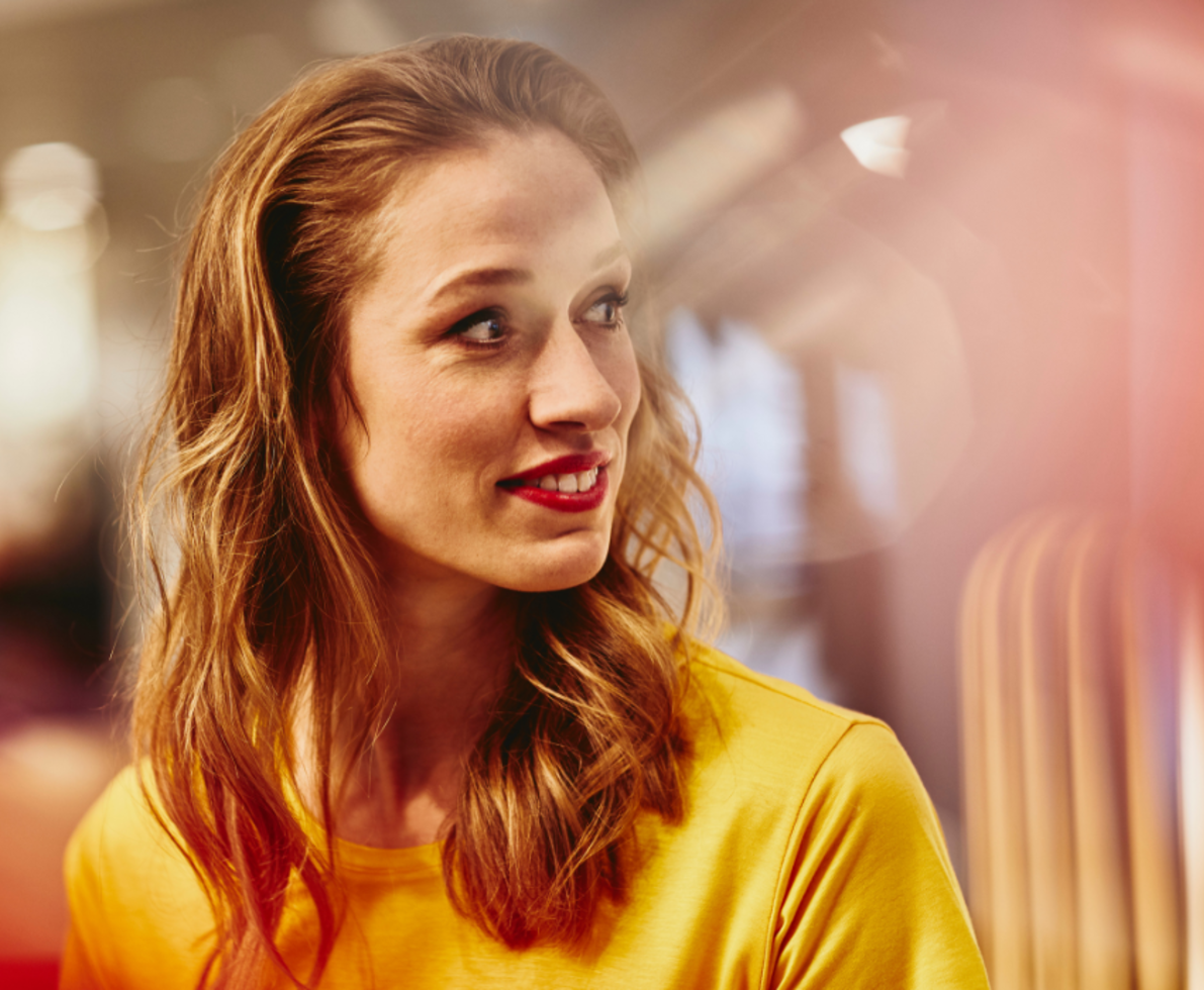 A woman in a yellow shirt looking at a distance