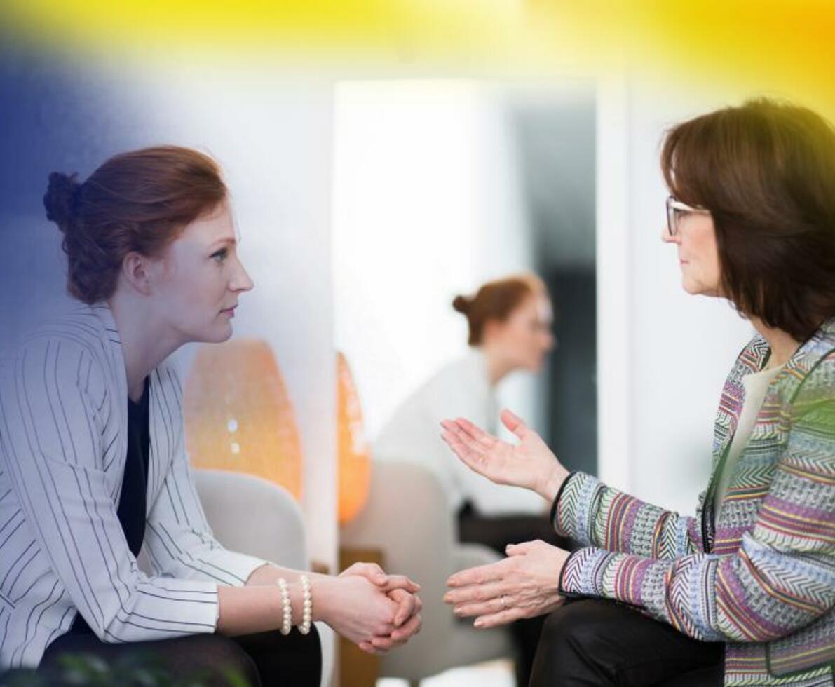 Two women talking in a counselling room with a mirror reflecting the woman on the left