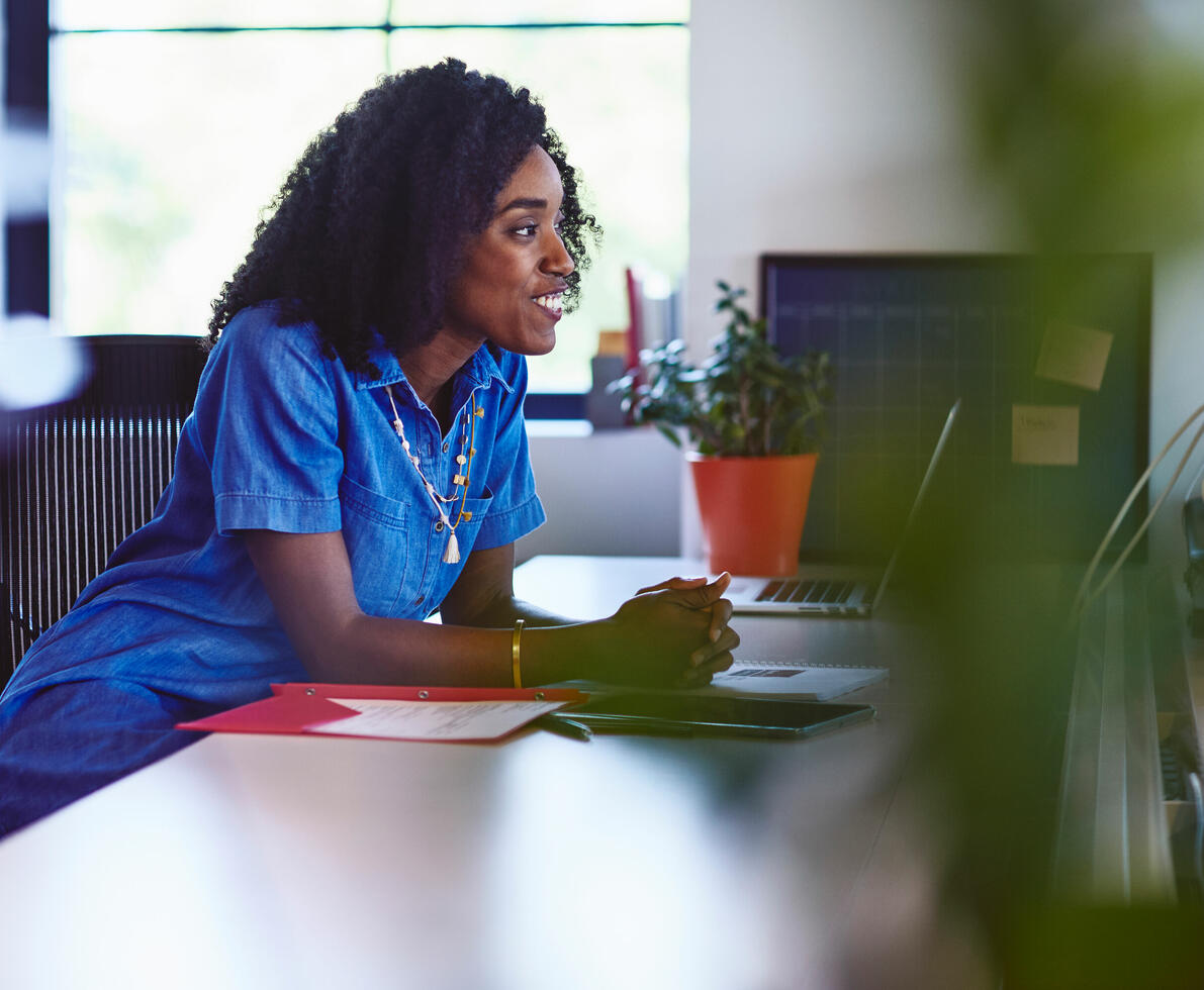 an image of a woman leaning on her desk smiling