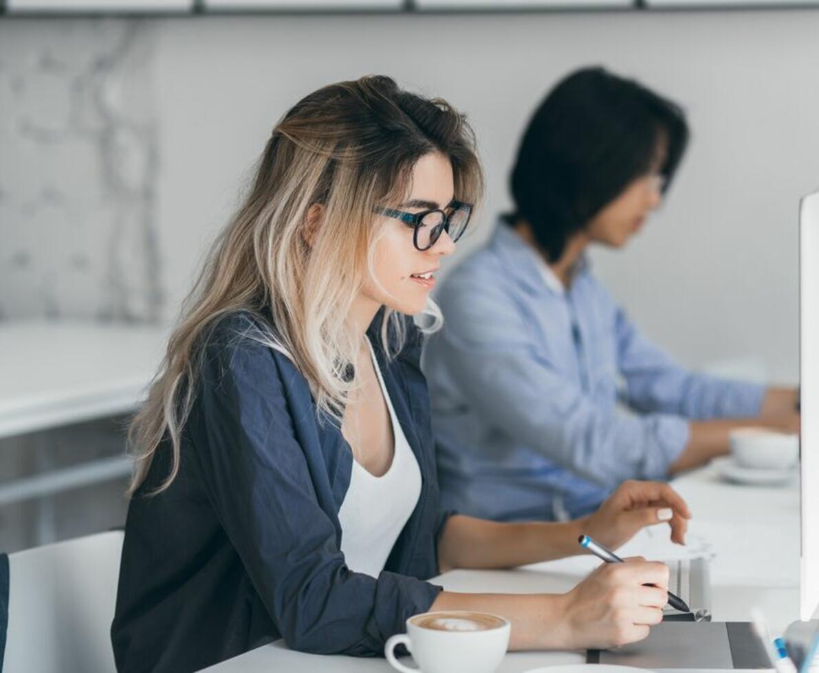 an image of a woman working on her desk with her coworker beside her