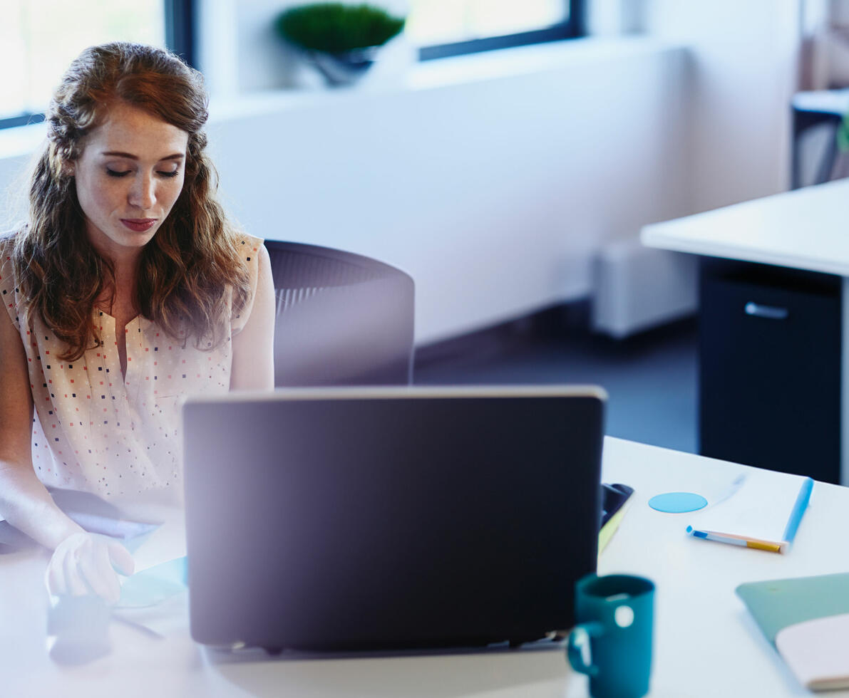 an image of a woman working in her office space in front of her laptop