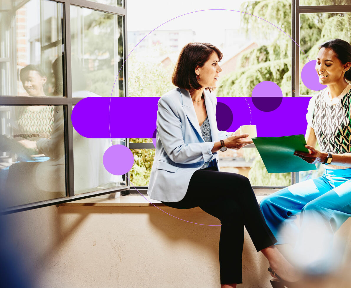 an image of two female sitting on a window sill looking at papers