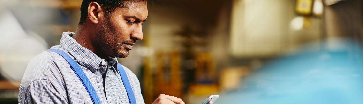 man looking down at tablet in a workshop environment