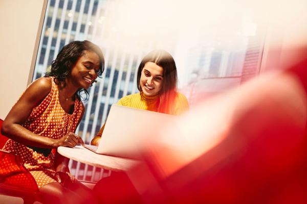 Two women working together on their laptops