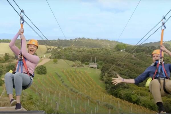 image of two people zip lining across a scenic landscape