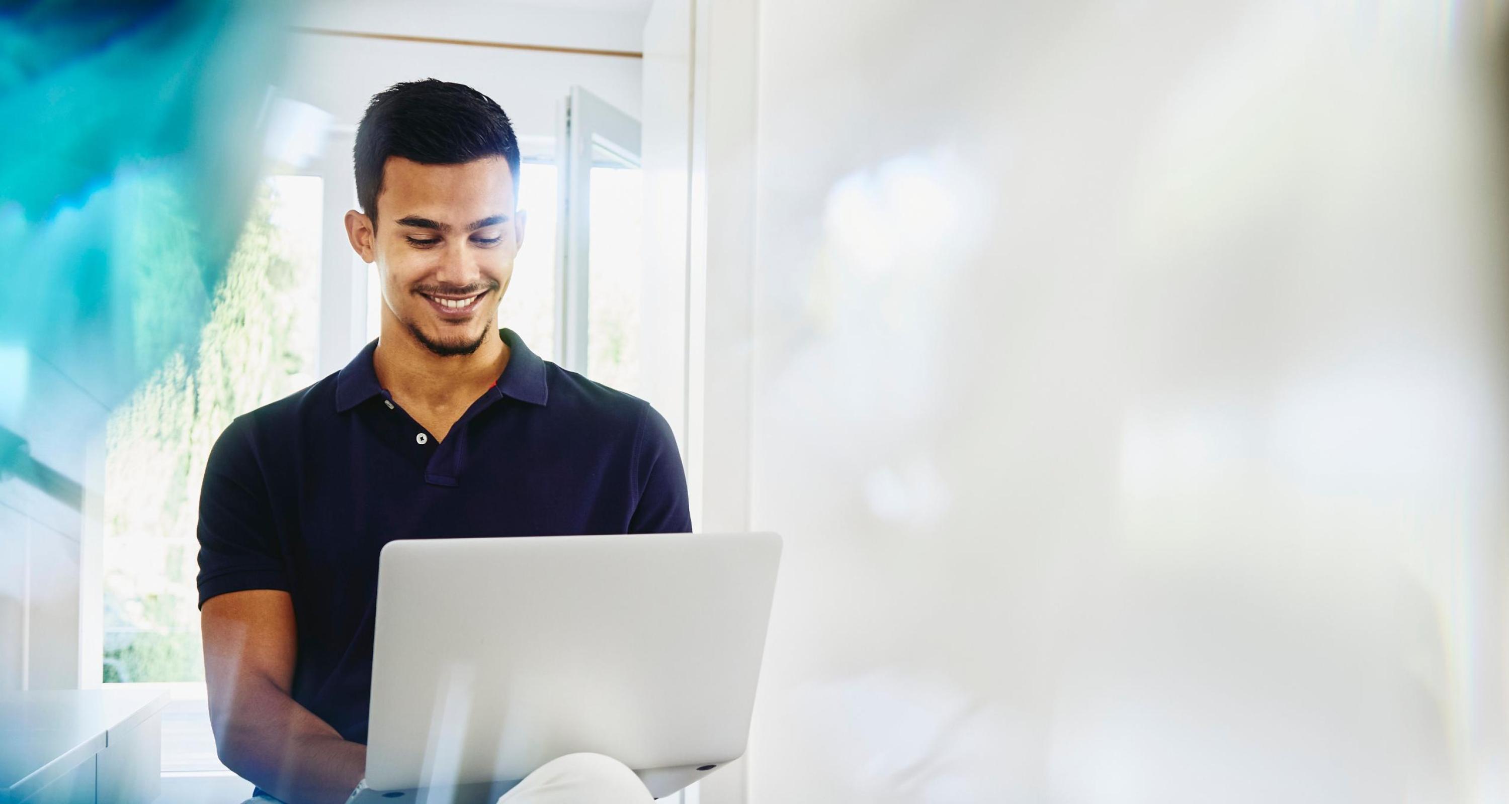 an image of a man wearing a navy shirt typing on his laptop