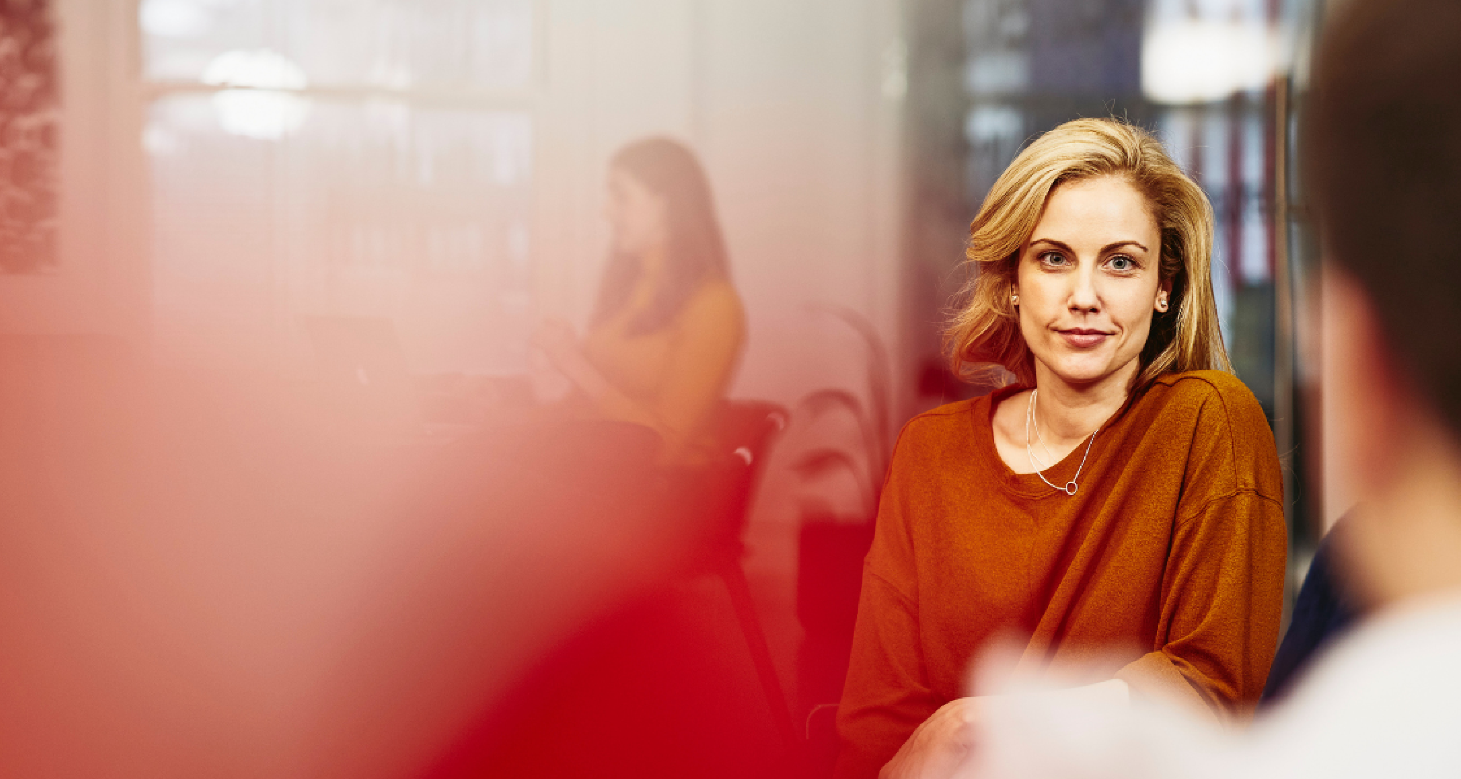 a woman wearing a maroon blouse chatting with her coworker 