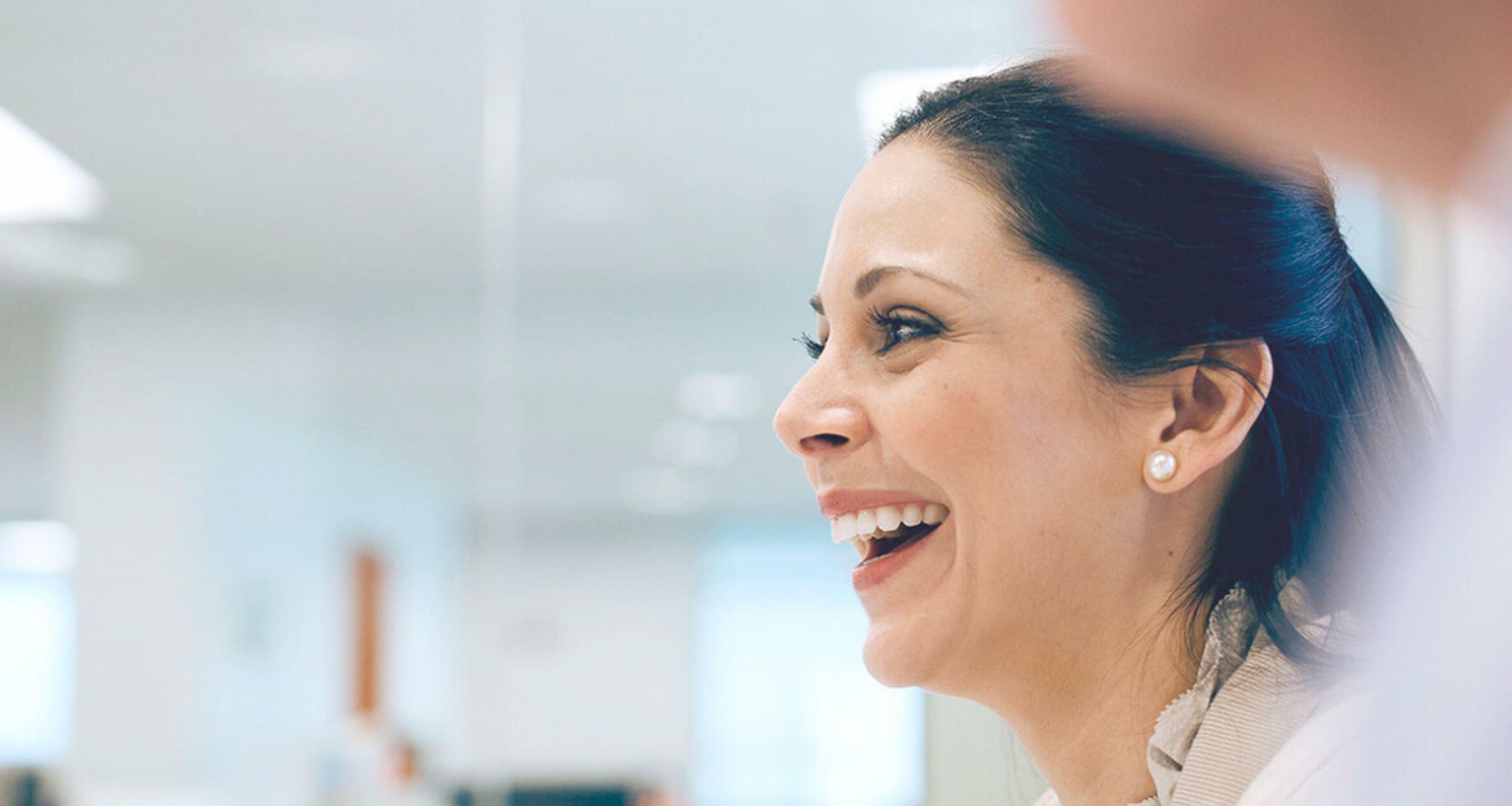 a woman looking to the left smiling widely