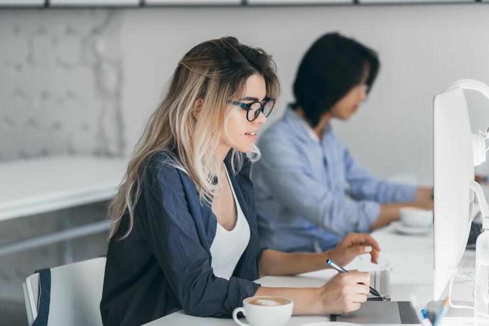 an image of a woman with glasses working in front of her desk