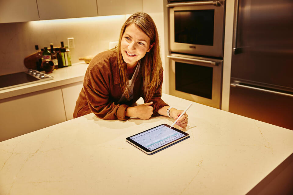 an image of a woman writing something on her tablet while looking to the left smiling