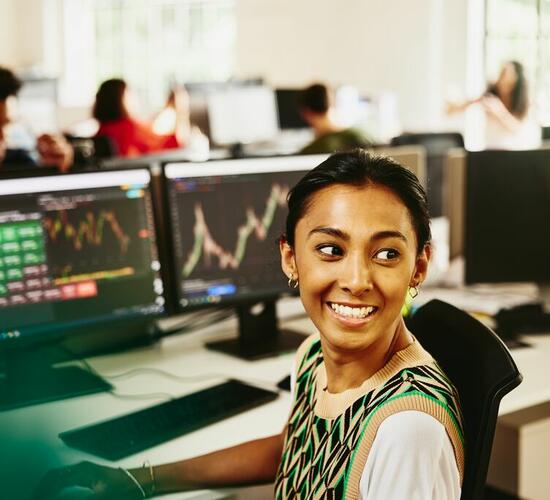 a woman smiling sitting at her desk whilst doing her work